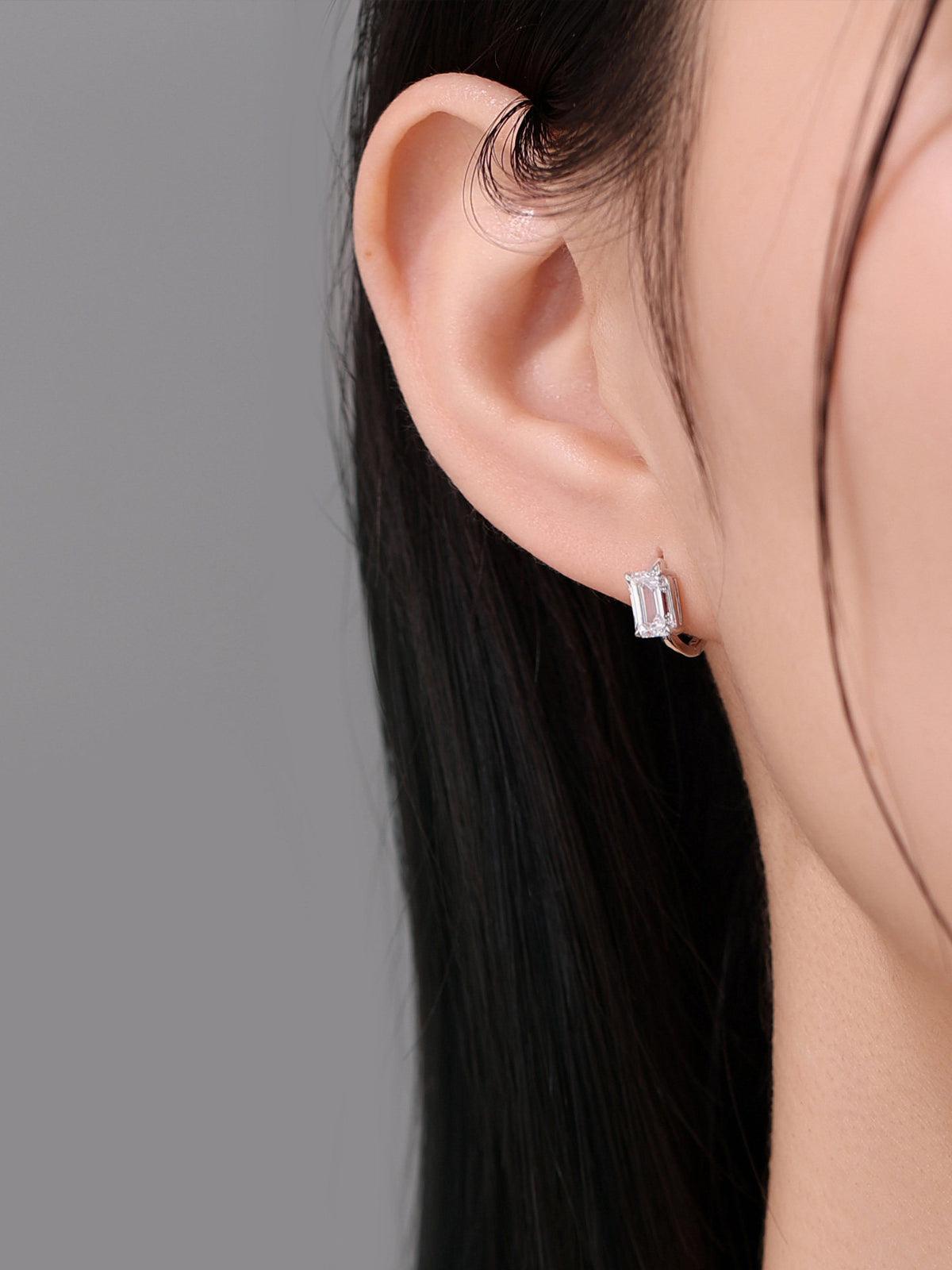 Emerald-cut diamond huggie earring side profile on model