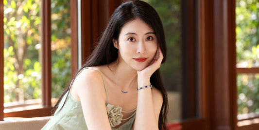 Woman in a sage green dress wearing a DANFÉE sapphire necklace and sapphire bracelet in white gold