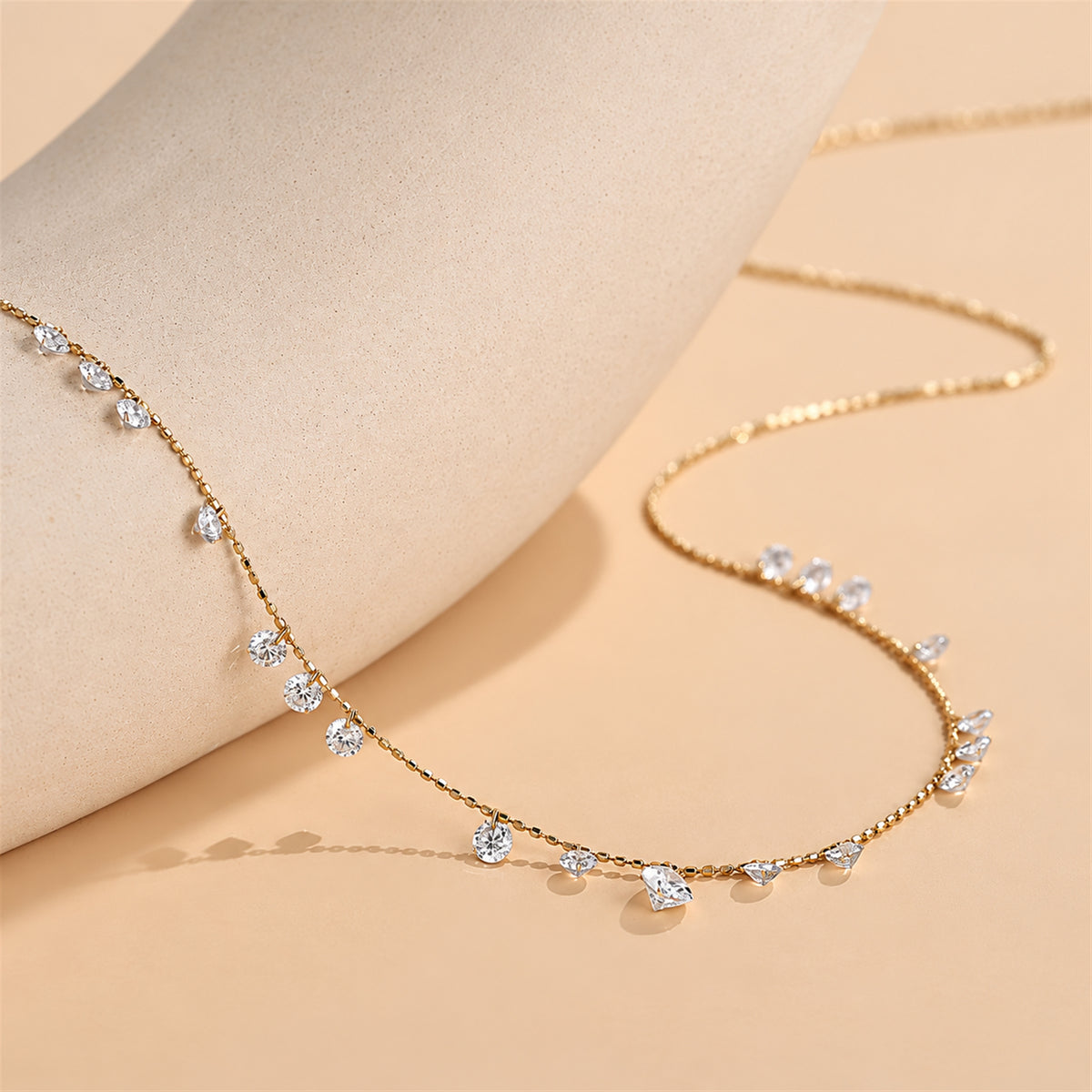 DANFÉE Muse lab-grown diamond station necklace — 18K yellow gold on warm beige stone display
