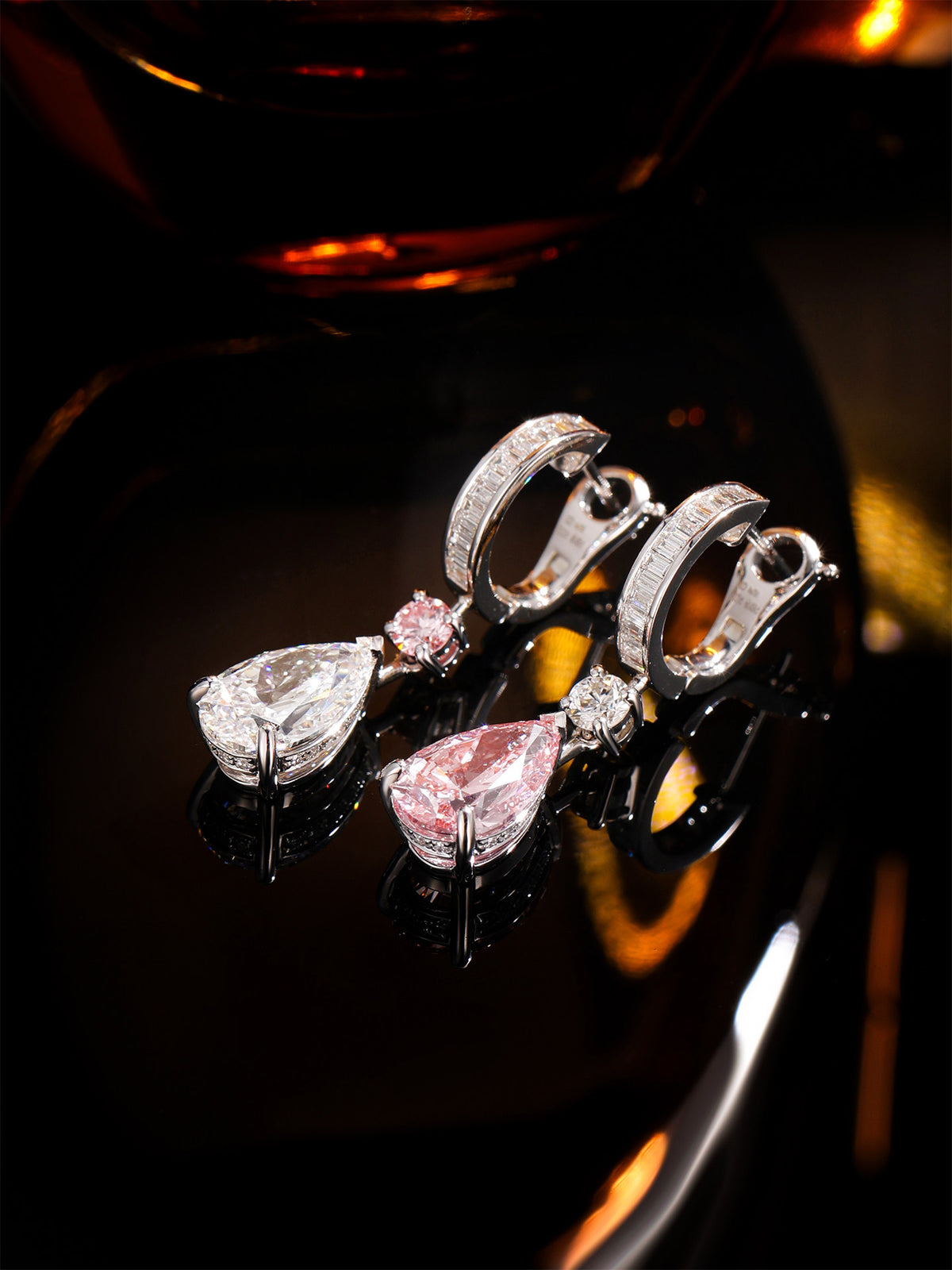 Rosée pink and white pear diamond earrings on a dark reflective surface