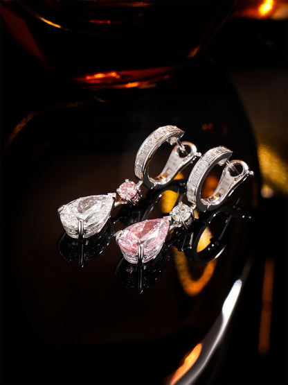 Rosée pink and white pear diamond earrings on a dark reflective surface