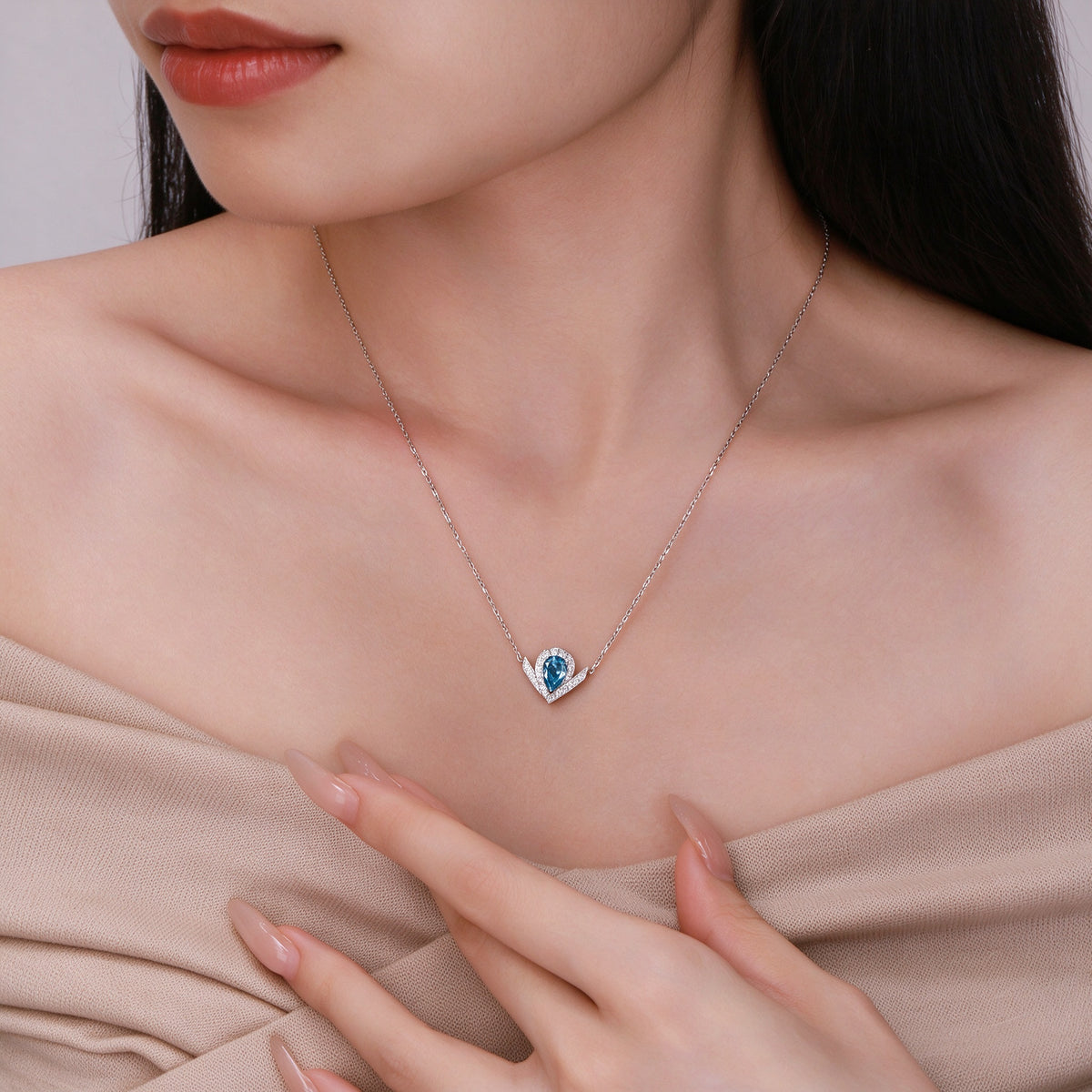 Model wearing the DANFÉE Chevron Pear Halo blue diamond necklace