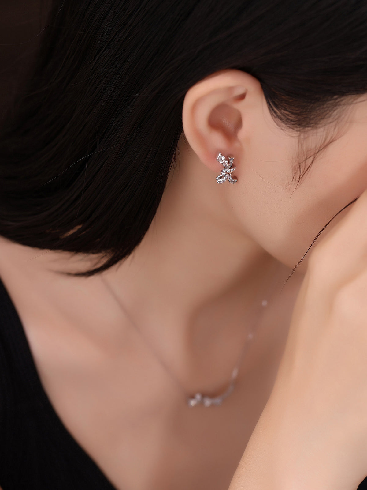 Platinum diamond knot earring on the ear, side profile