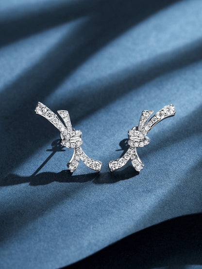 Lab-grown diamond love-knot earrings on blue paper