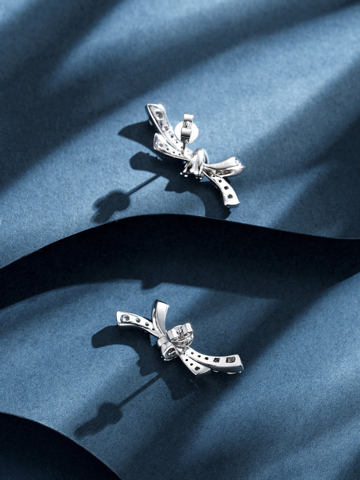 Reverse of PT950 diamond bow earrings on blue paper