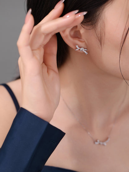 Diamond bow stud earring worn with a navy blazer