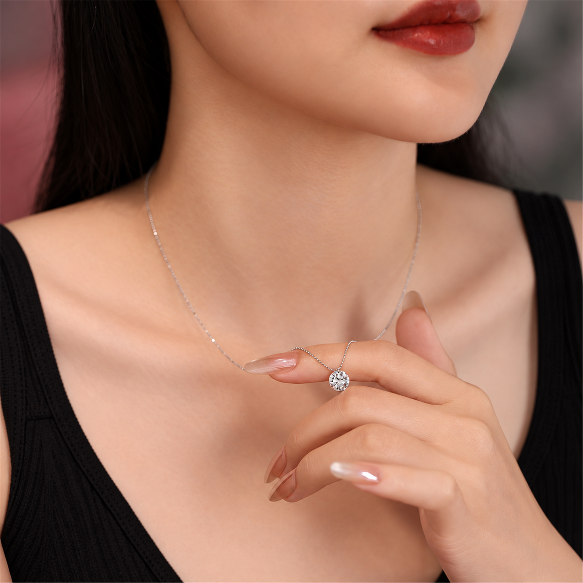 Round solitaire diamond pendant held at the neckline with a black top; edited supplier styling photo