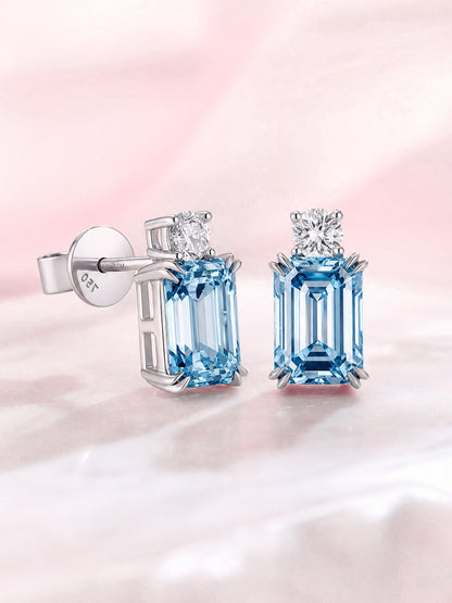 Side view of blue emerald-cut diamond stud earrings in 18K white gold claw setting