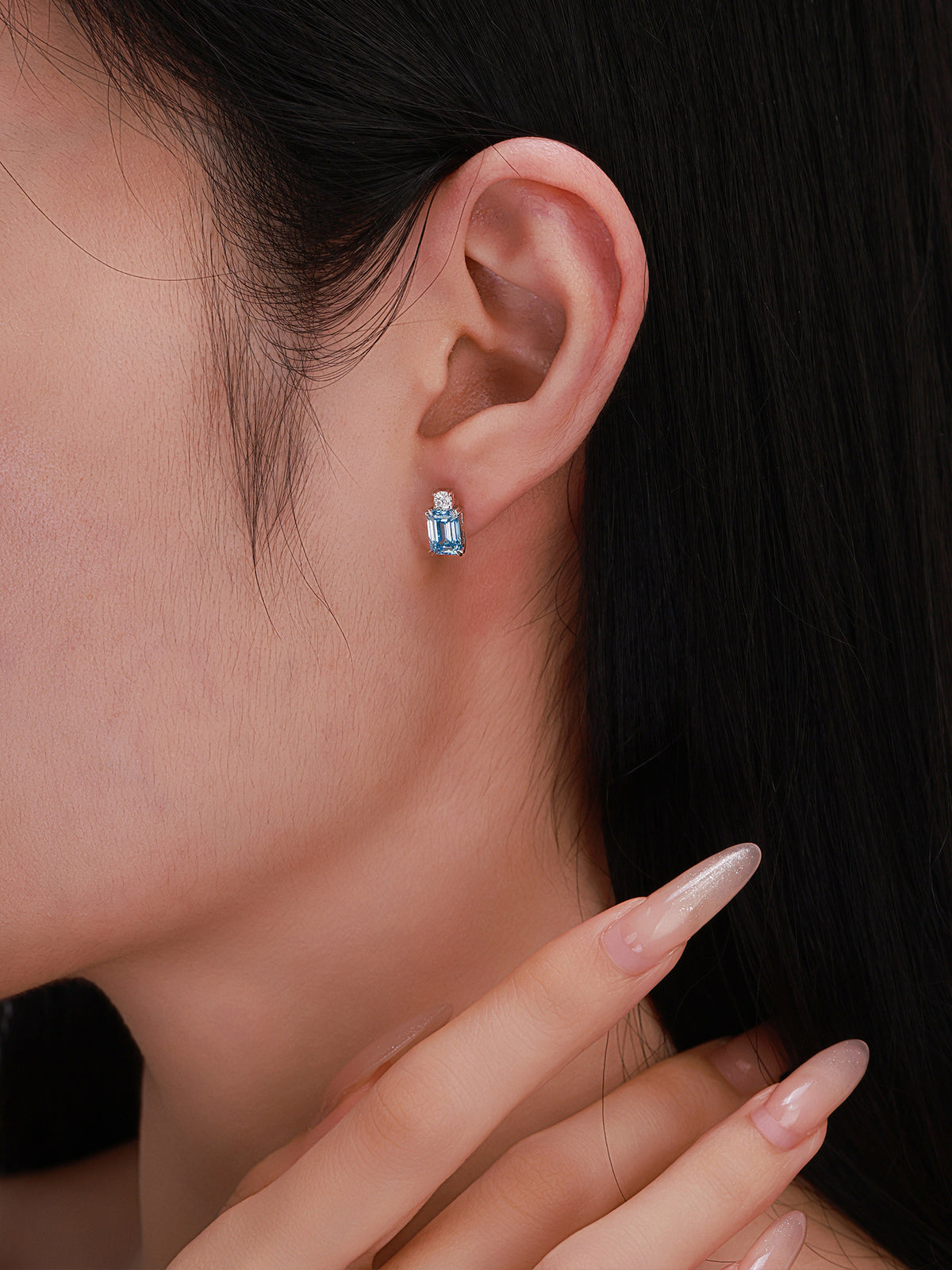 Close-up of fancy vivid blue emerald-cut diamond stud earring worn