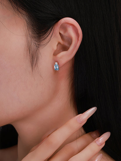 Close-up of fancy vivid blue emerald-cut diamond stud earring worn