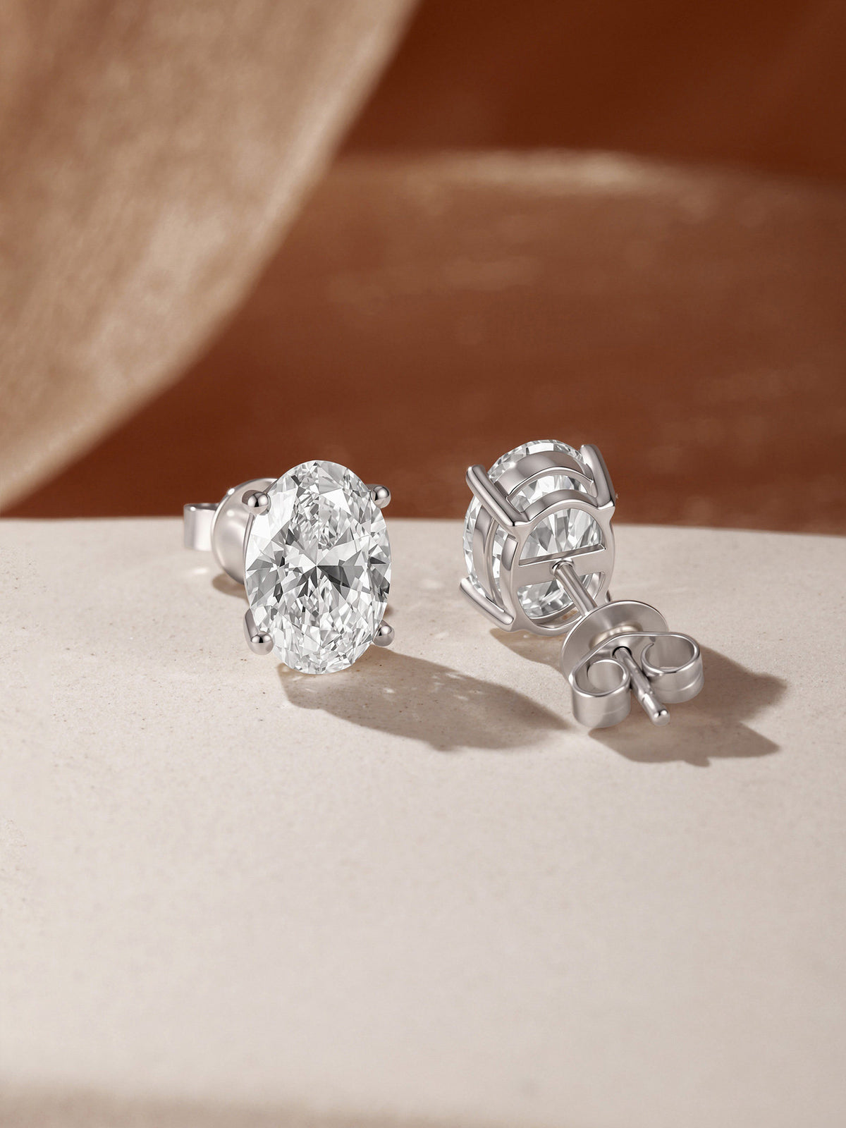 Céleste oval diamond stud earrings showing four-claw setting and 18K gold butterfly back