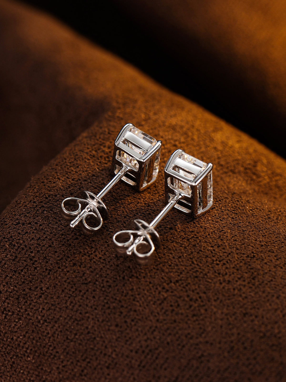 Side view of four-claw emerald-cut diamond studs with 18K gold butterfly backs