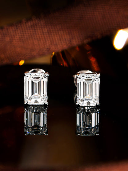 Emerald-cut lab-grown diamond solitaire studs reflected on a dark mirror
