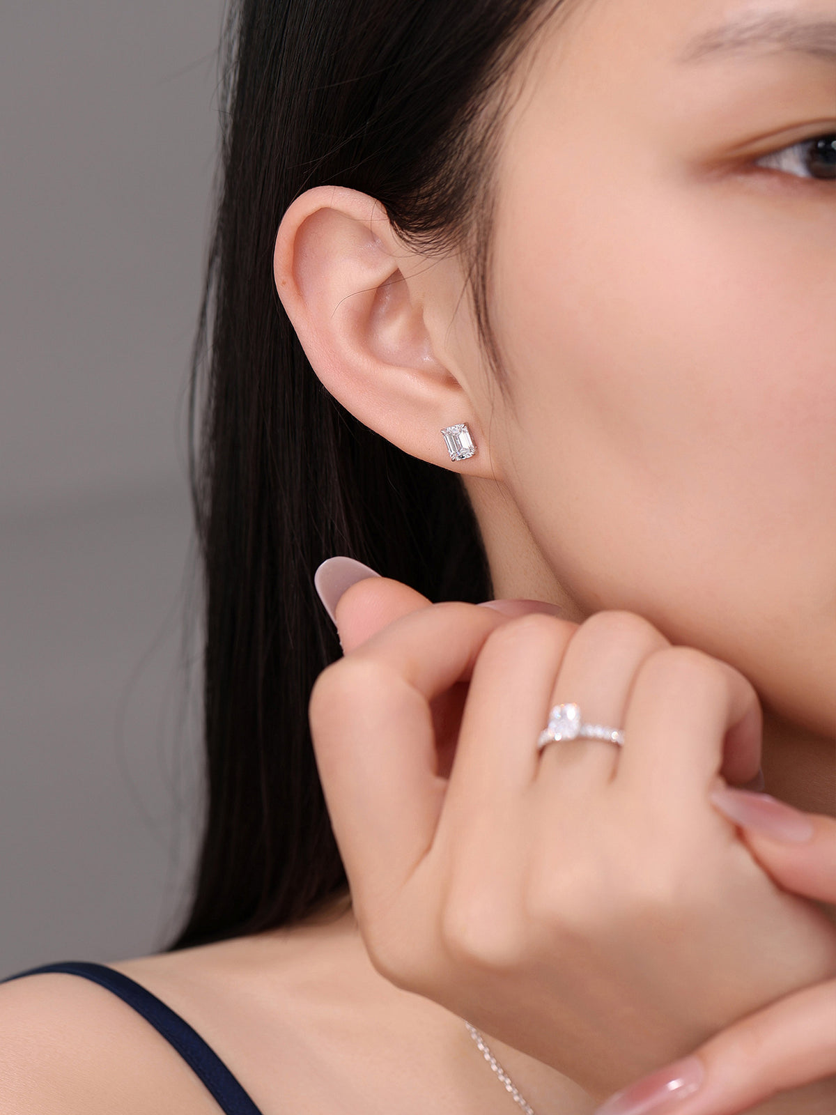 Emerald-cut diamond solitaire stud worn on the ear with a diamond ring