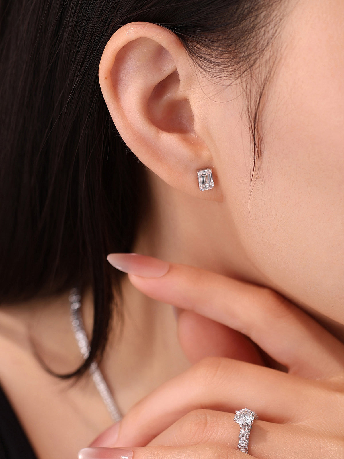 Close-up of the 18K white gold emerald-cut diamond stud earring on a model