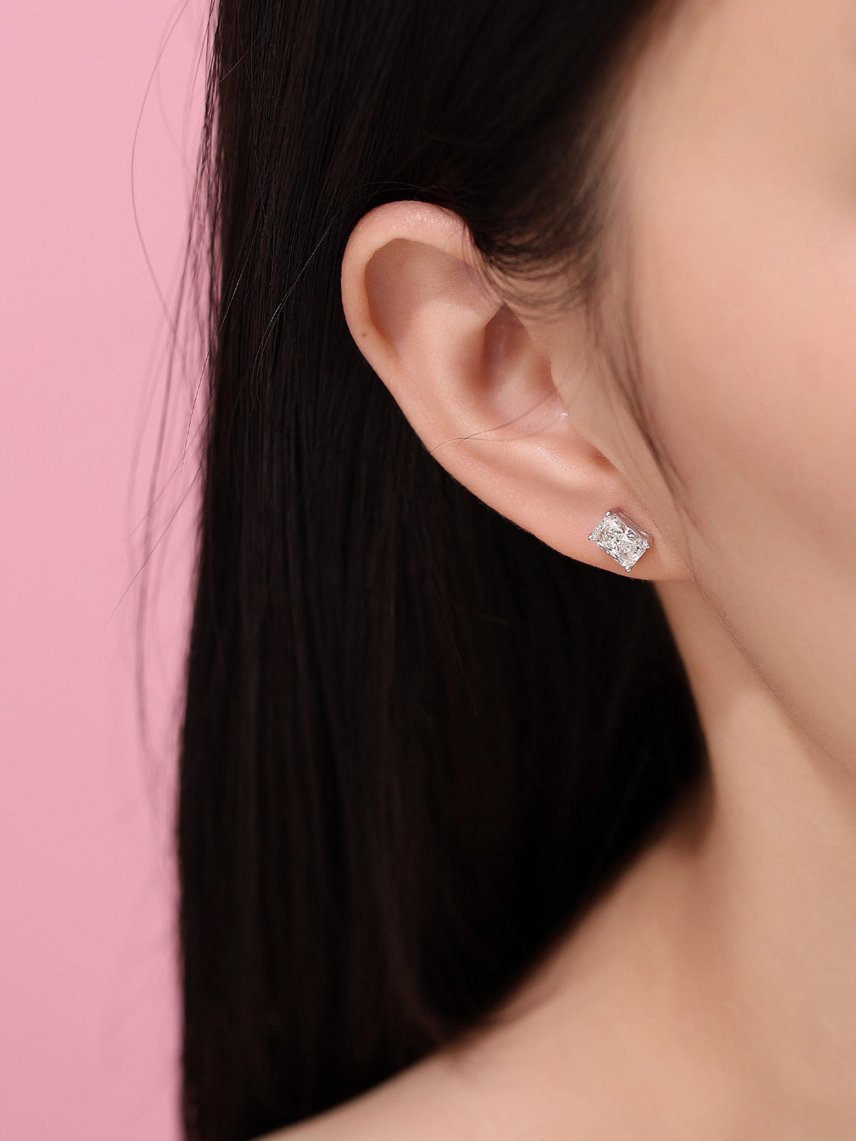 Radiant-cut lab-grown diamond stud earring worn on the ear against a pink background