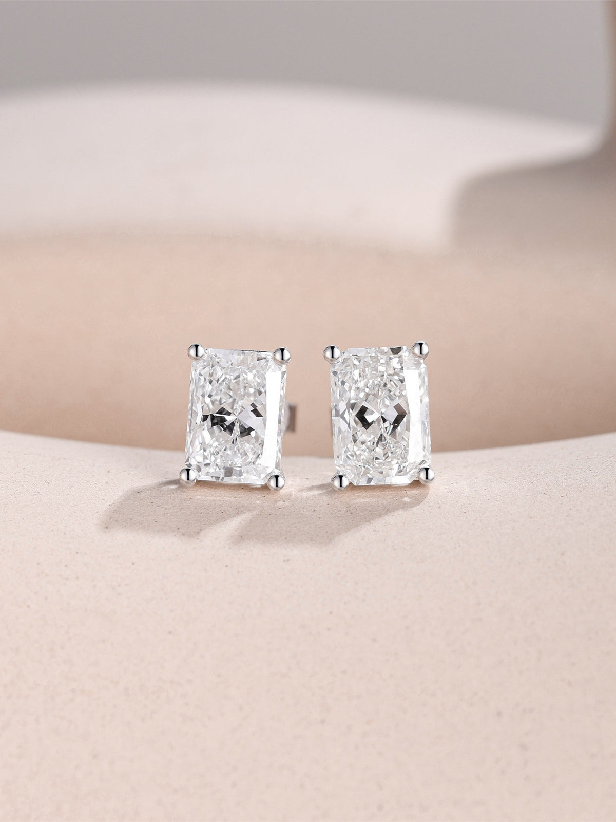 1 carat radiant-cut lab-grown diamond studs in 18K white gold on a sand-toned stone