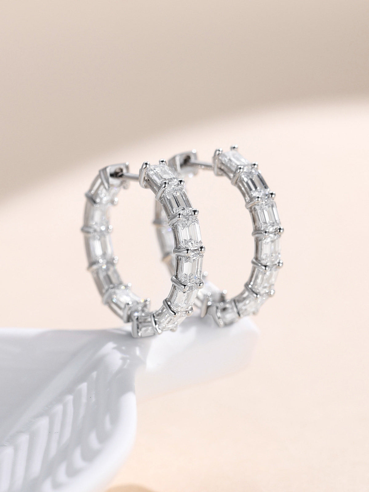Close-up of emerald-cut lab-grown diamonds set inside and out along platinum hoop earrings