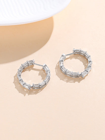 Emerald-cut diamond hoop earrings with hinged snap closure on a beige background