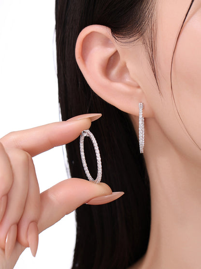 Model holding one inside-out diamond hoop earring to show its size