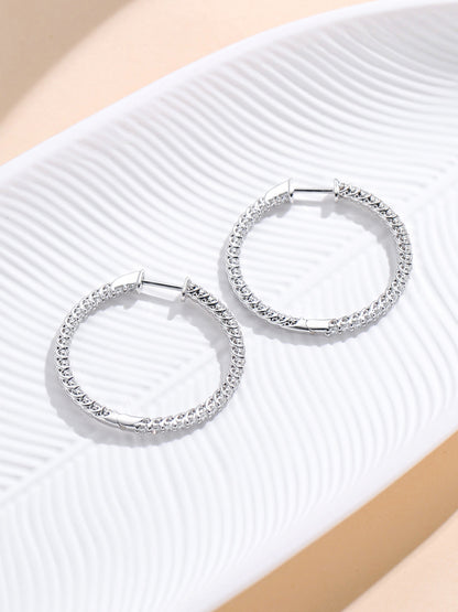 Inside-out diamond hoop earrings resting on a white leaf dish