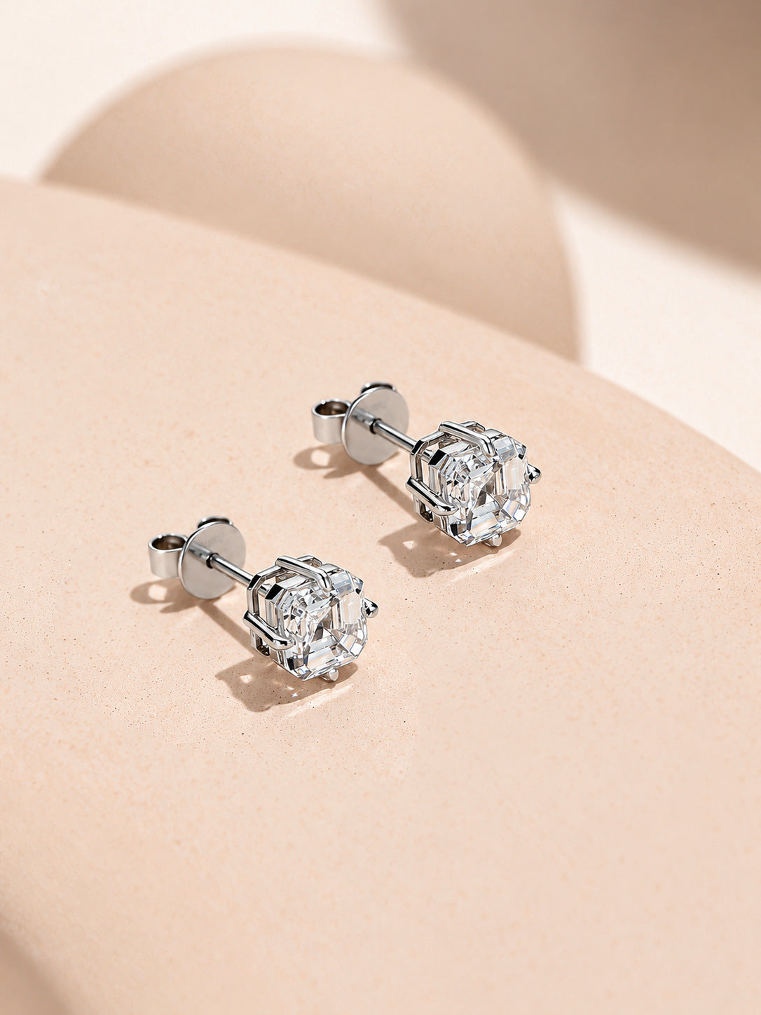 Side view of the Asscher-cut diamond stud earrings showing the 18K white gold basket and gold butterfly backs