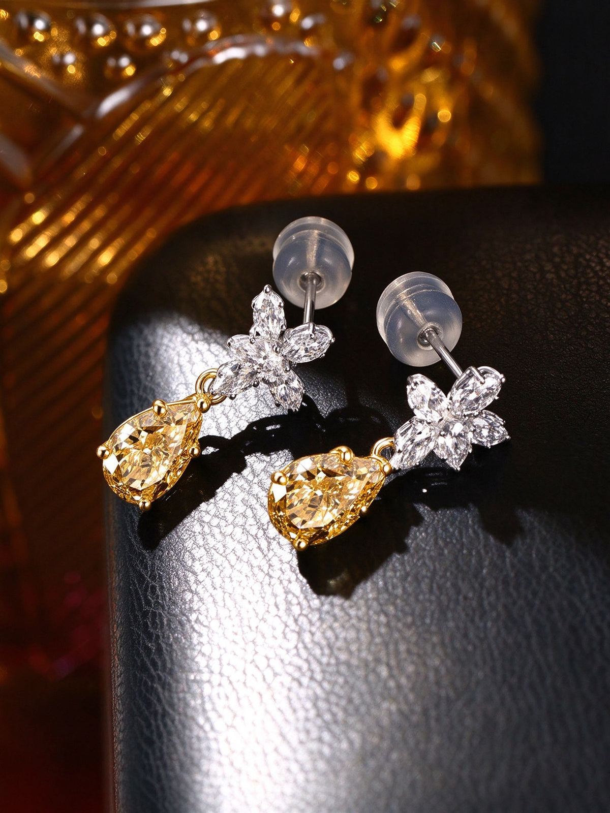 Pair of Floraison pear-cut yellow diamond earrings on black leather