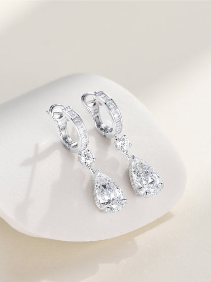 Pair of pear-cut lab-grown diamond drop earrings in 18K white gold resting on a white stone