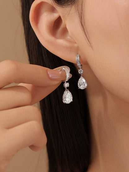 Model holding the baguette huggie diamond drop earring beside her ear