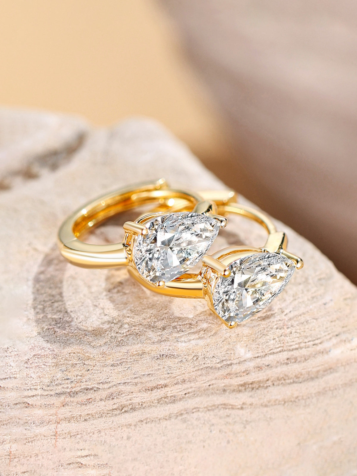 Pear-cut lab-grown diamond huggie earrings resting on stone