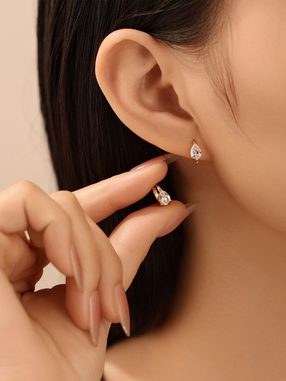 Pear-cut diamond huggie earring worn on the ear