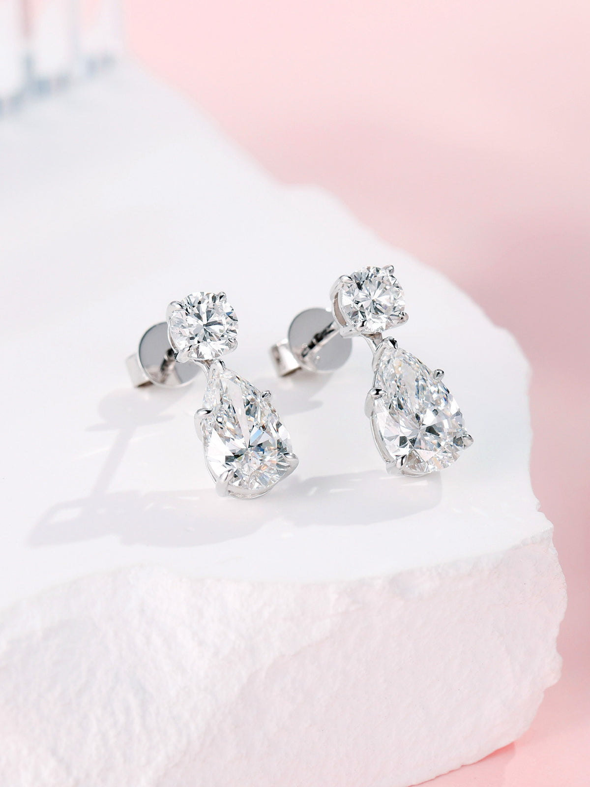 Pear-shaped lab-grown diamond drop earrings with round diamond studs on white stone