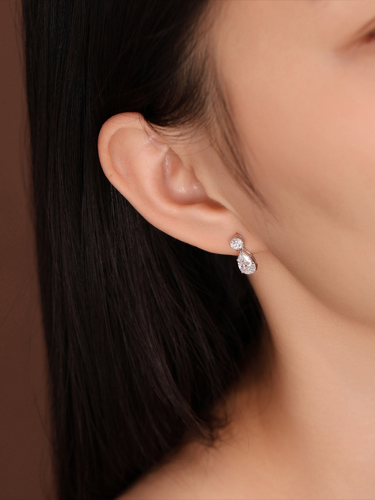 Model wearing pear and round lab-grown diamond drop earrings