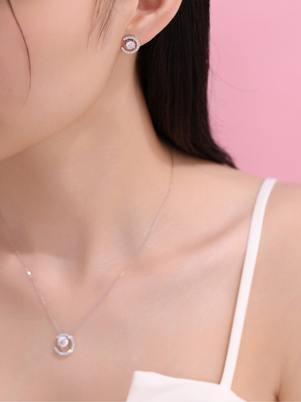 Model wearing the Lune crescent diamond earring and pendant against pink