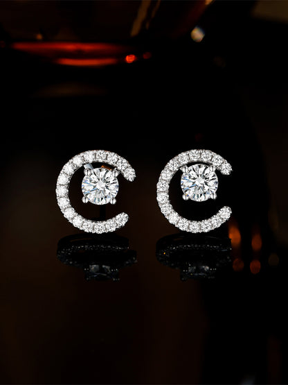 Lune crescent diamond earrings glowing against a dark background