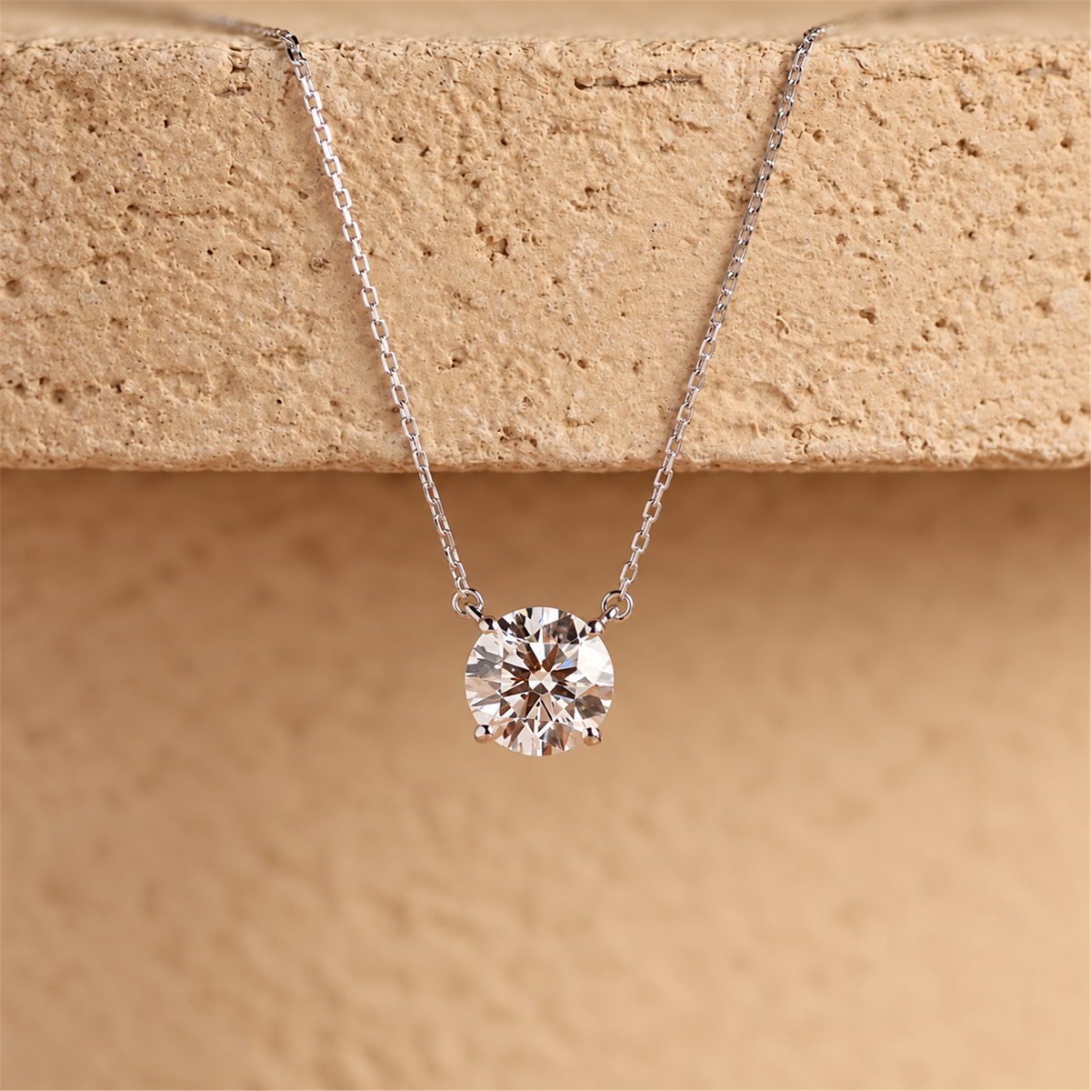 18K white gold four-prong diamond necklace against warm natural stone