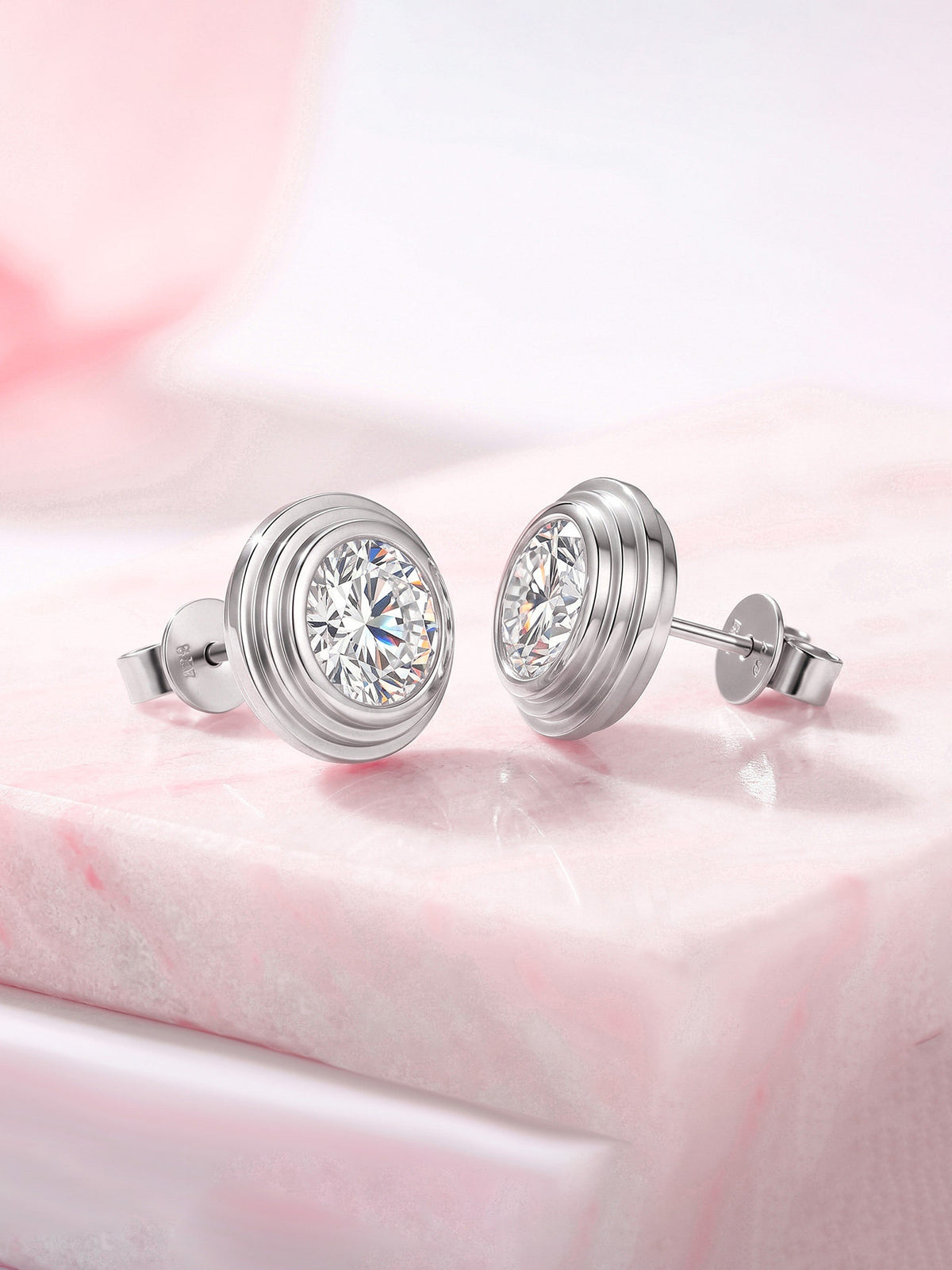 Tiered bezel lab-grown diamond stud earrings in 18K white gold on pink marble