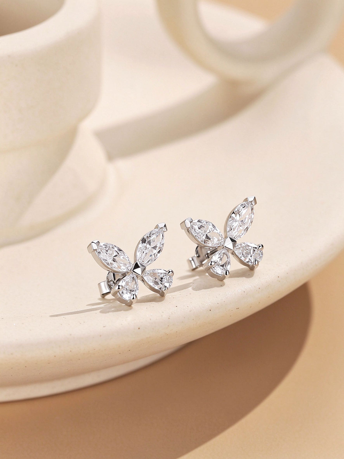 Marquise and pear-cut lab-grown diamond butterfly stud earrings on ivory ceramic