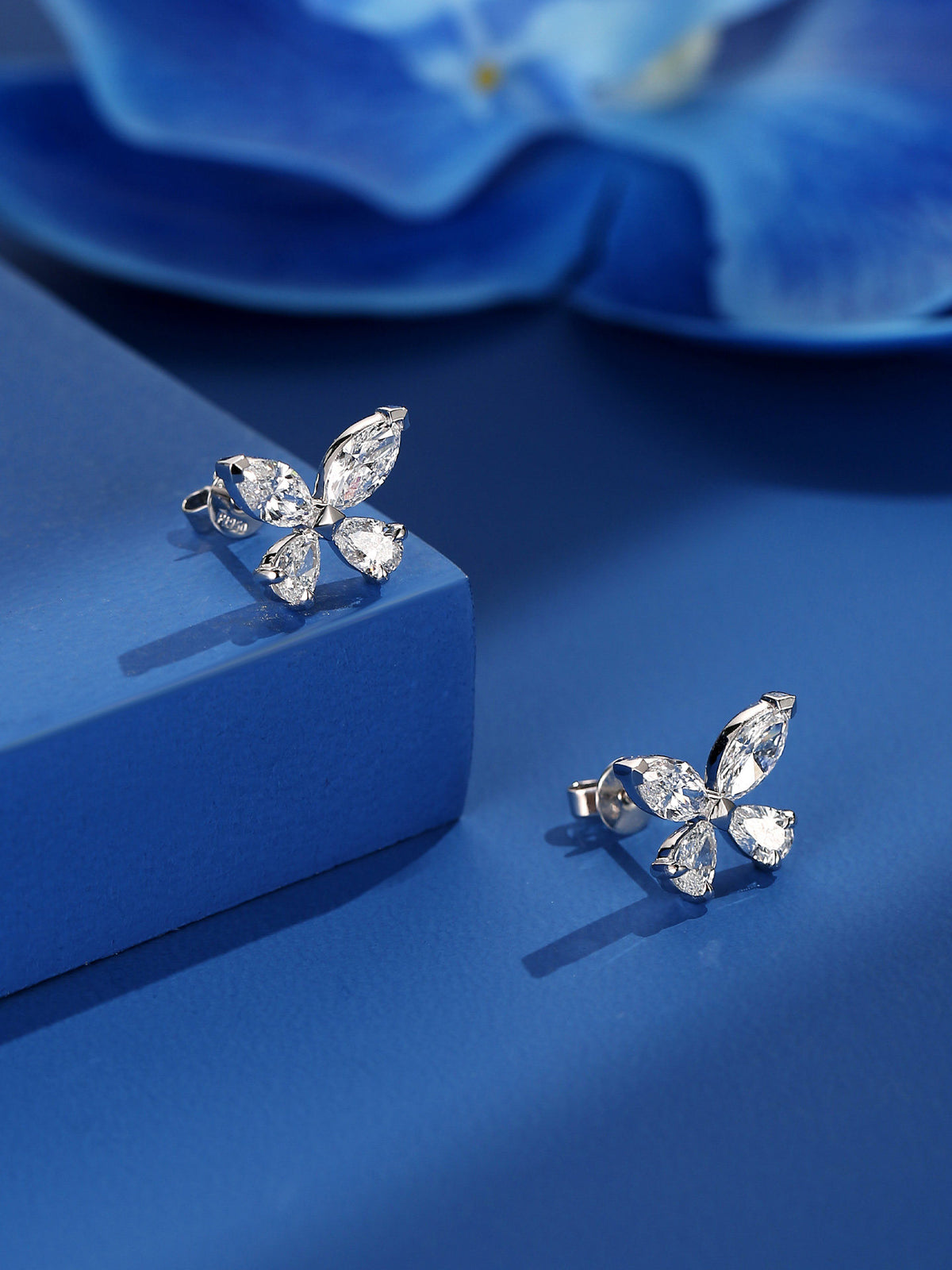 Butterfly lab-grown diamond stud earrings on a sapphire-blue stand