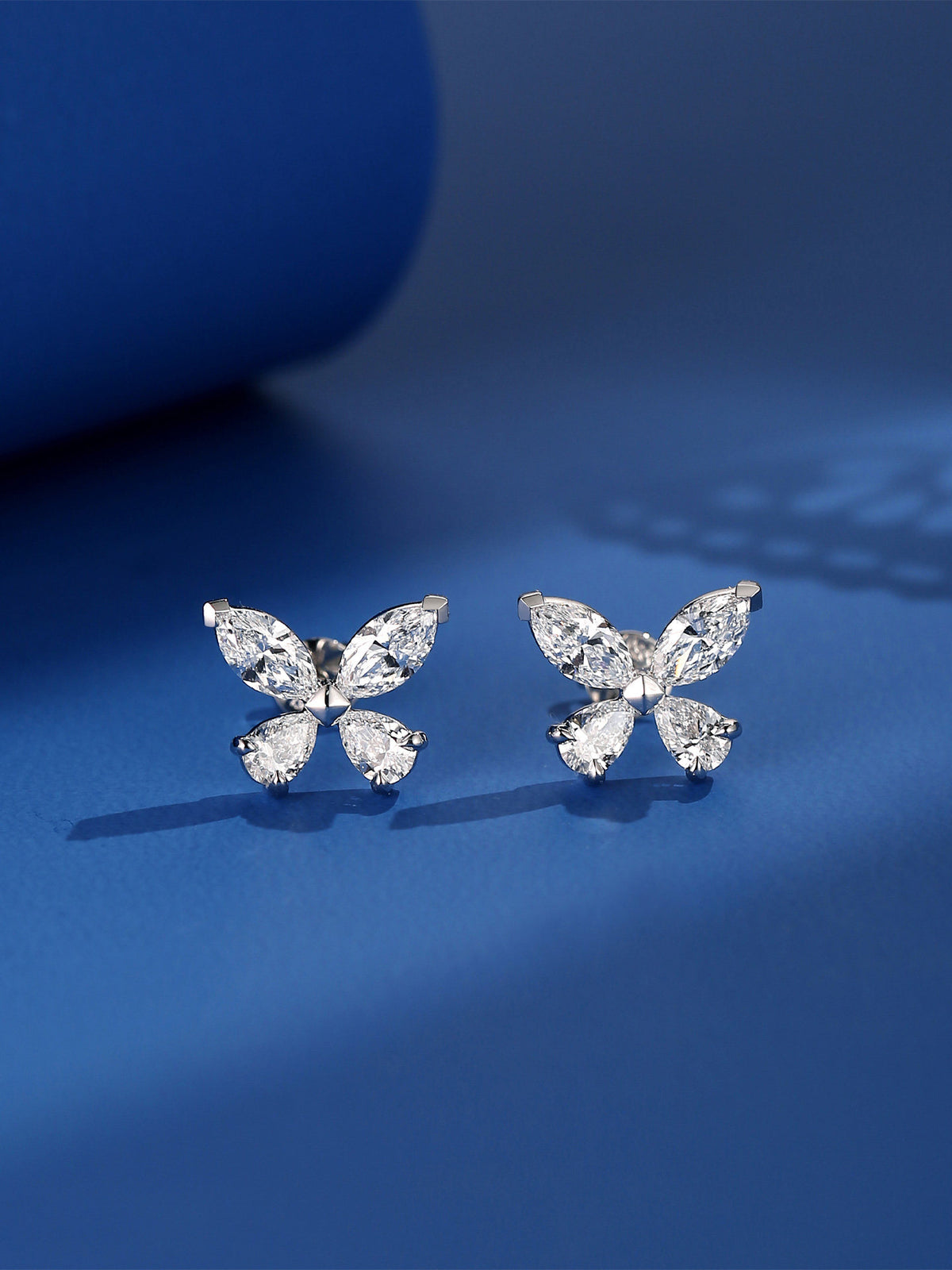 Pair of marquise and pear diamond butterfly studs on deep blue