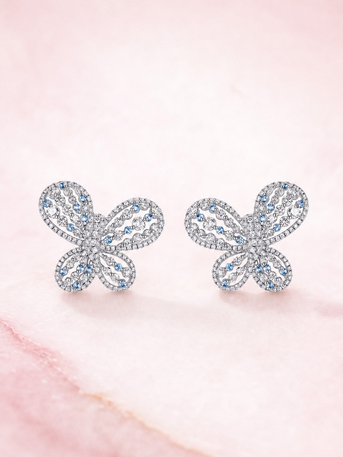 Papillon butterfly diamond stud earrings, front view on pink marble