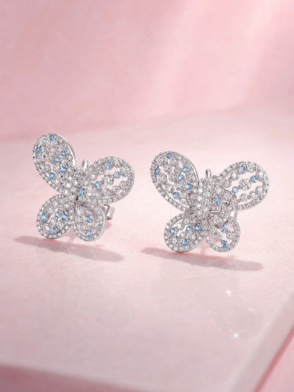 Papillon butterfly diamond stud earrings, angled view on pink marble