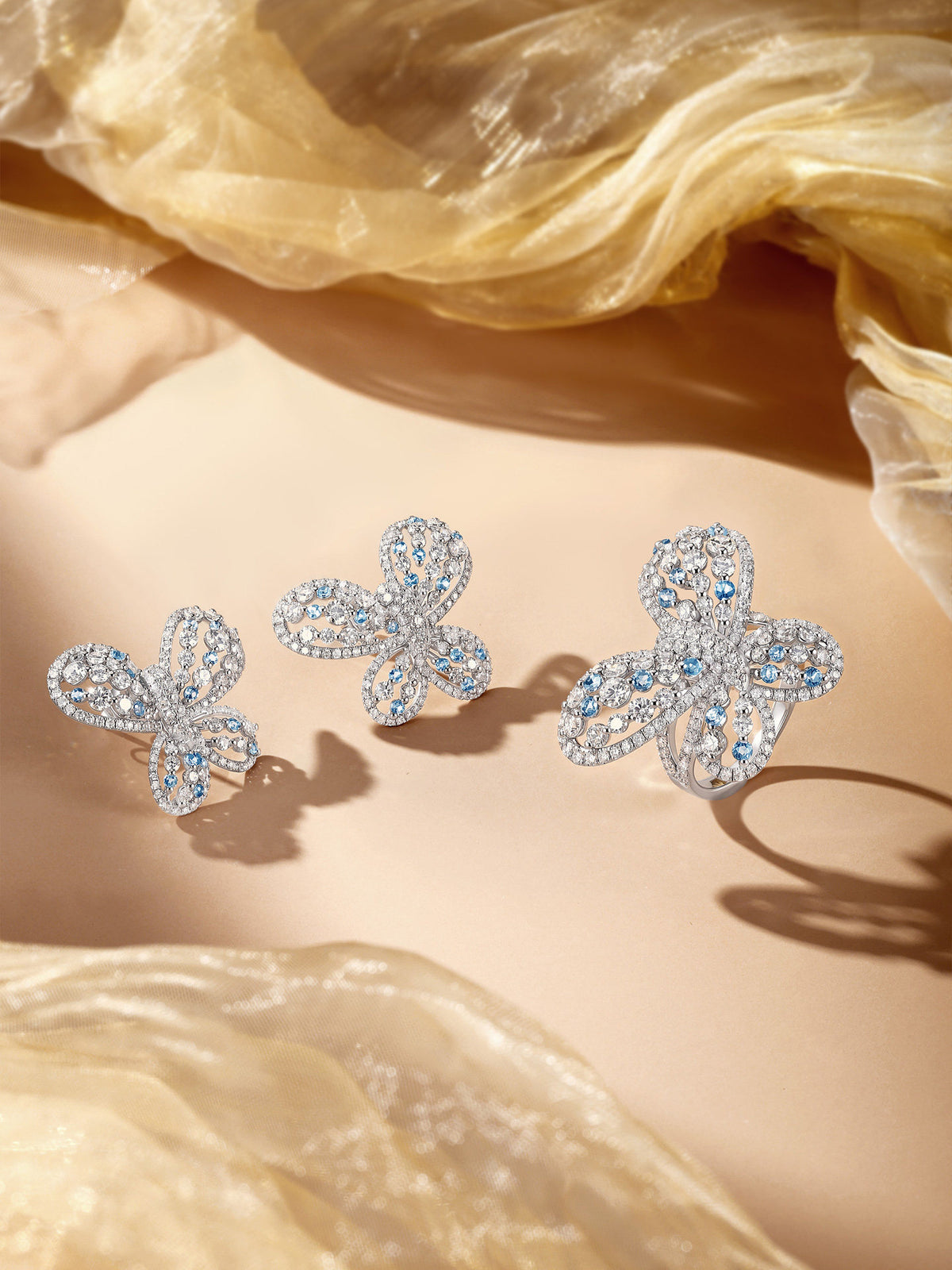 Papillon butterfly diamond earrings styled on champagne silk