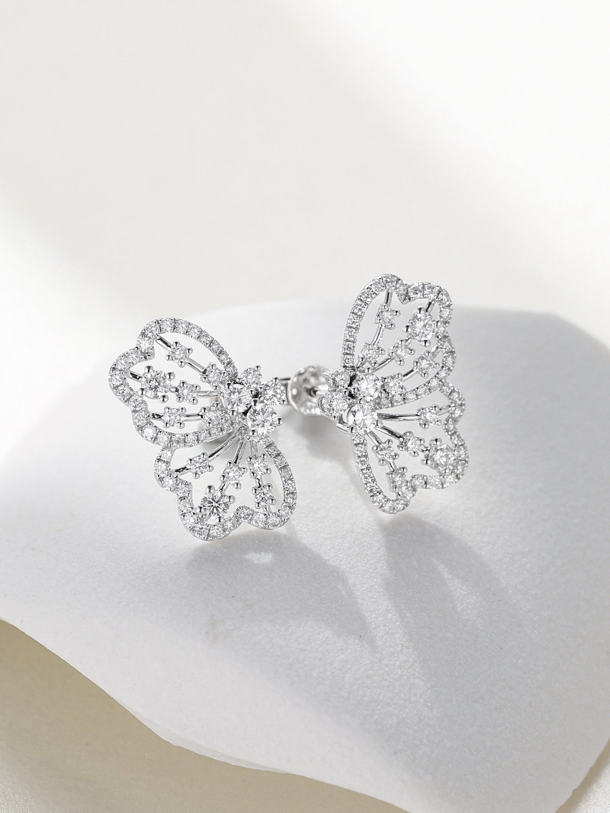 Papillon openwork butterfly diamond earrings resting on white stone