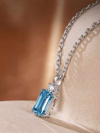 DANFÉE Parfum 2 carat emerald-cut blue diamond pendant on sandstone, angled view