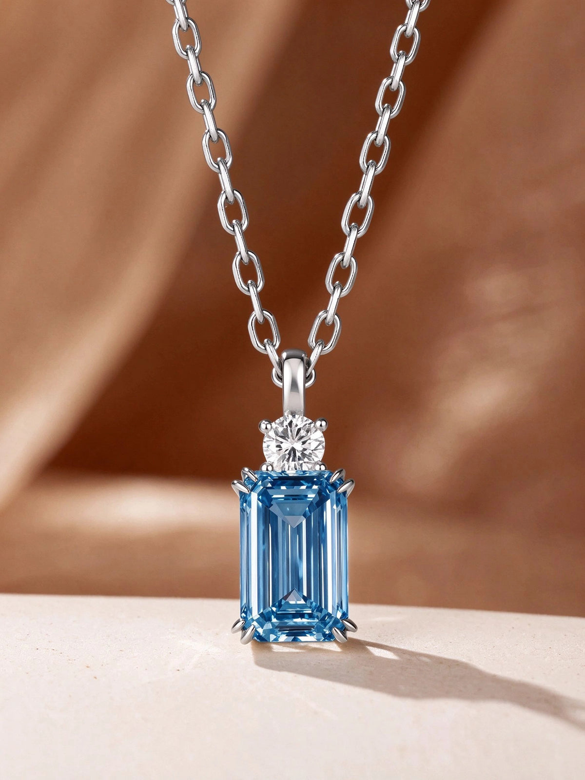 DANFÉE Parfum Fancy Vivid Blue emerald-cut diamond necklace on a warm backdrop