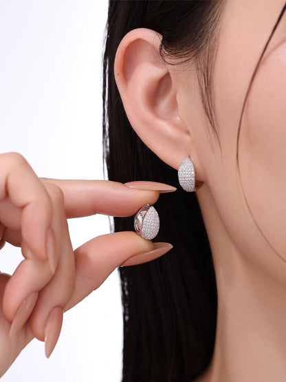 Model holding pavé lab-grown diamond huggie earring to show scale