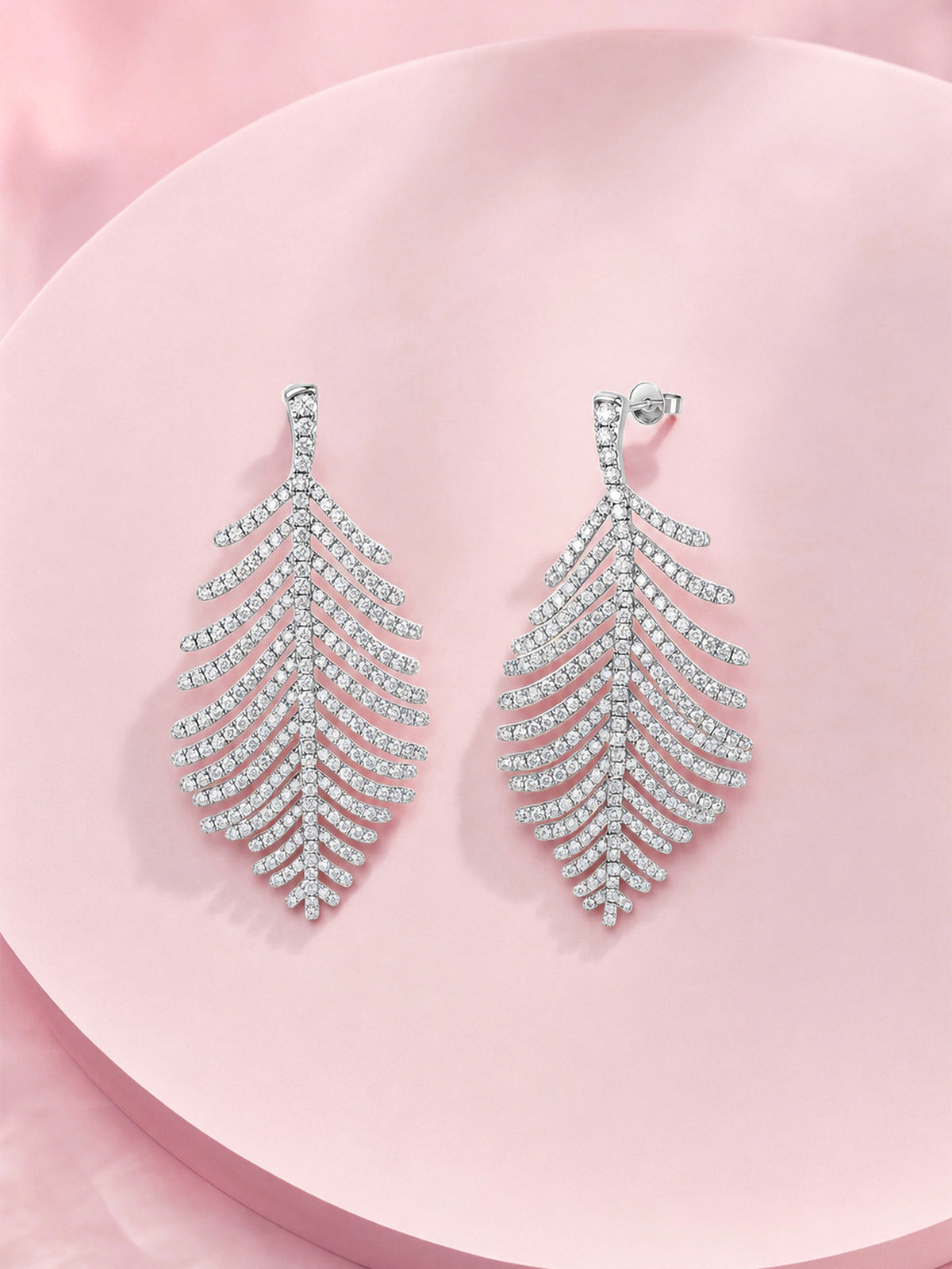 Large feather pavé diamond drop earrings in 18K white gold on a pink backdrop