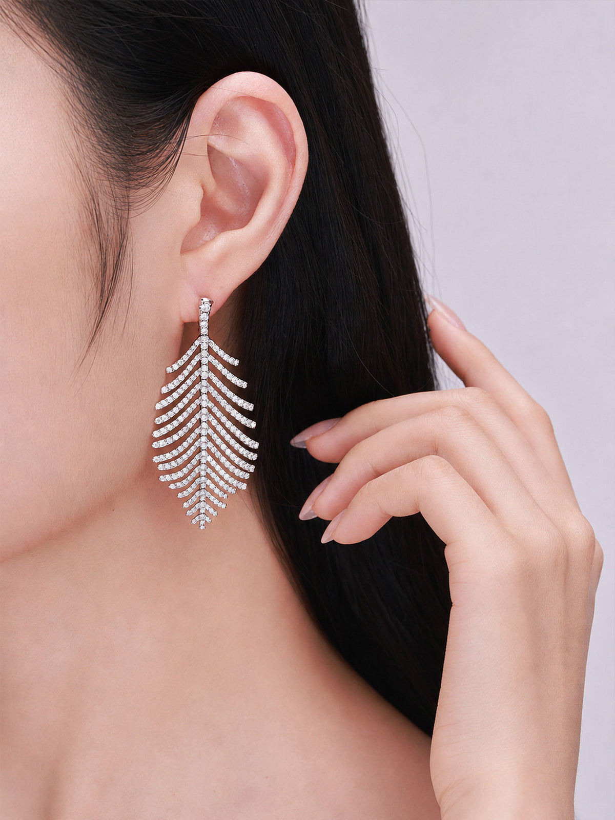 Close-up of the feather pavé diamond drop earring worn on the ear