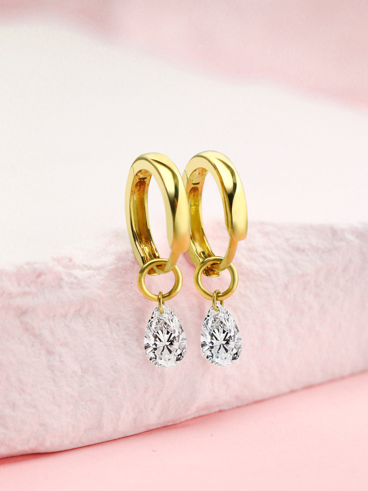 Pear-cut lab-grown diamond drop huggie earrings in 18K gold on a pink stone